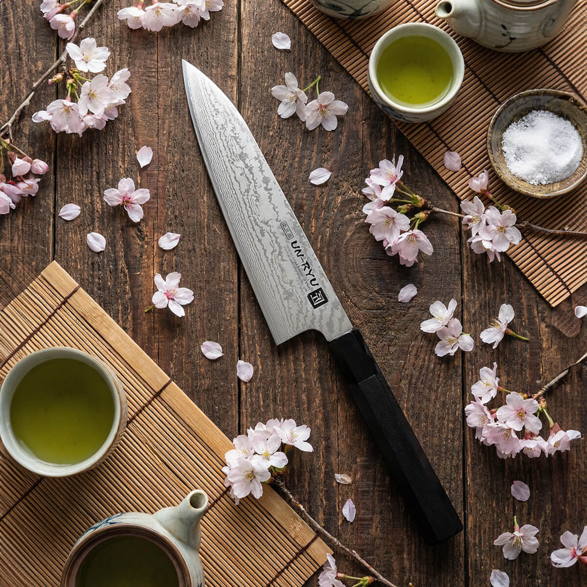Damast Santokumesser liegt auf einem Tisch mit Matcha Tee und Kirschblüten